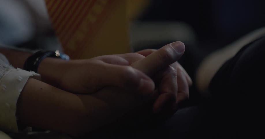 A man and woman holding hands in a movie theater