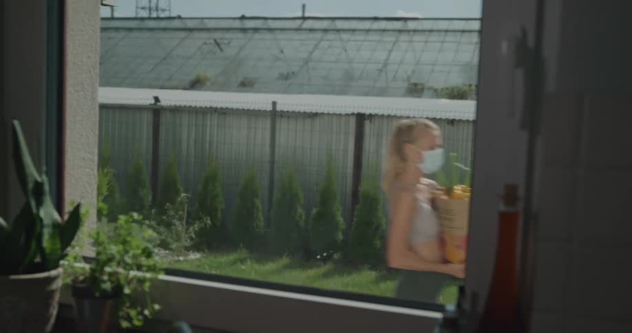 A woman can be seen through a window as she carries a bag of groceries