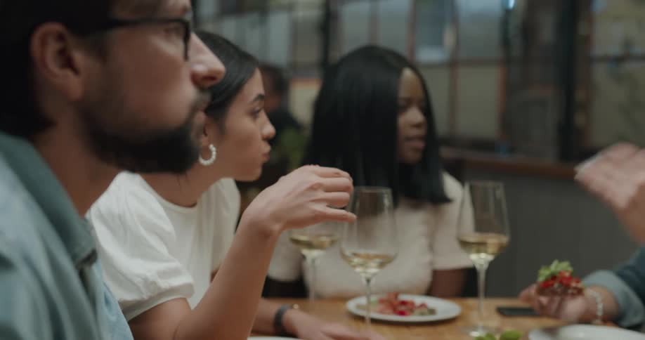 A group of friends sitting in restaurant talking eating and drinking wine and beer