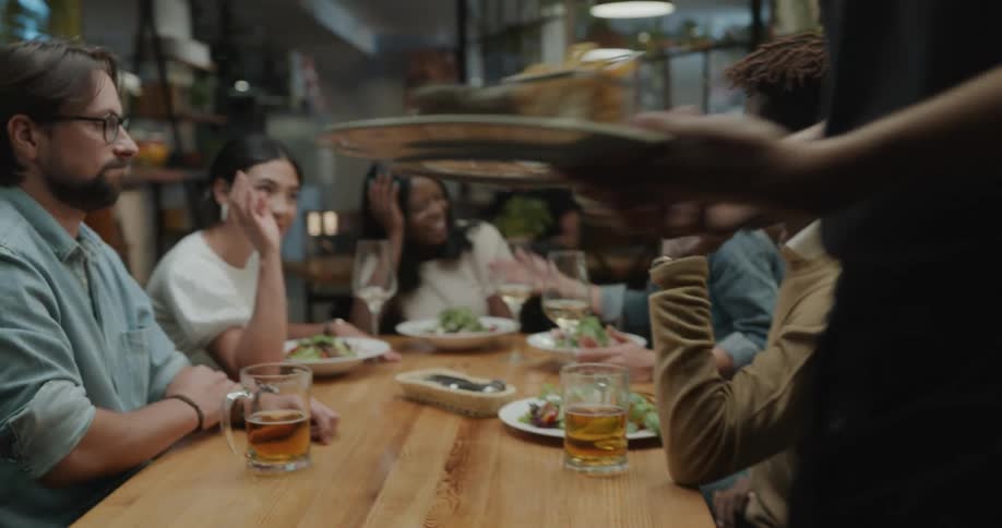 A group of young adults gather for food and drinks at a restaurant