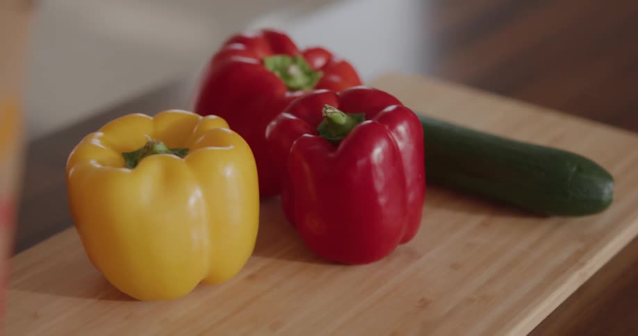 A person placing vegetables on a cutting board on a table