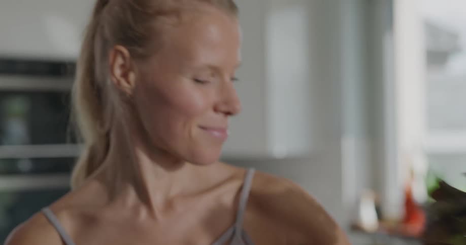 Blonde woman with a ponytail takes out vegetables from the bag in the kitchen