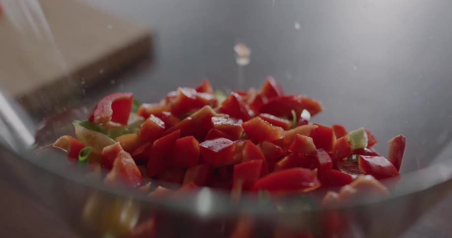 Woman cuts a red bell pepper and puts it on the salad in the bowl