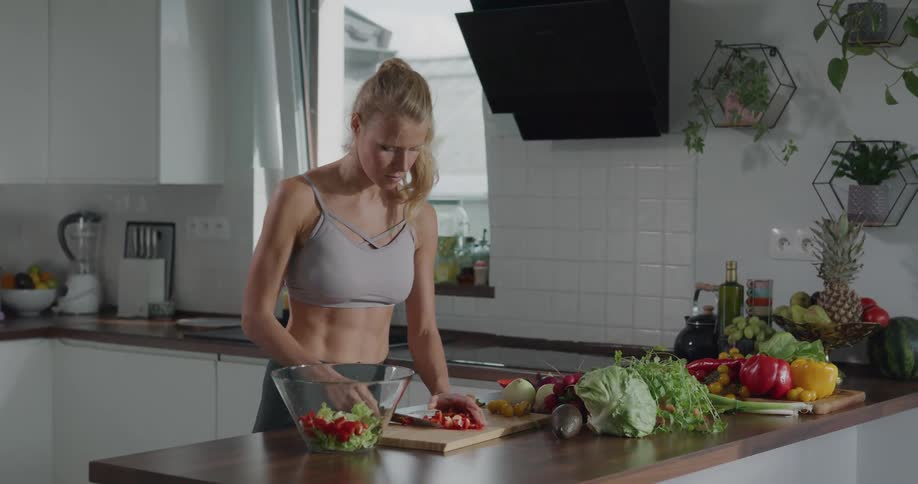 A woman cuts vegetables in her kitchen and places the pieces in a bowl