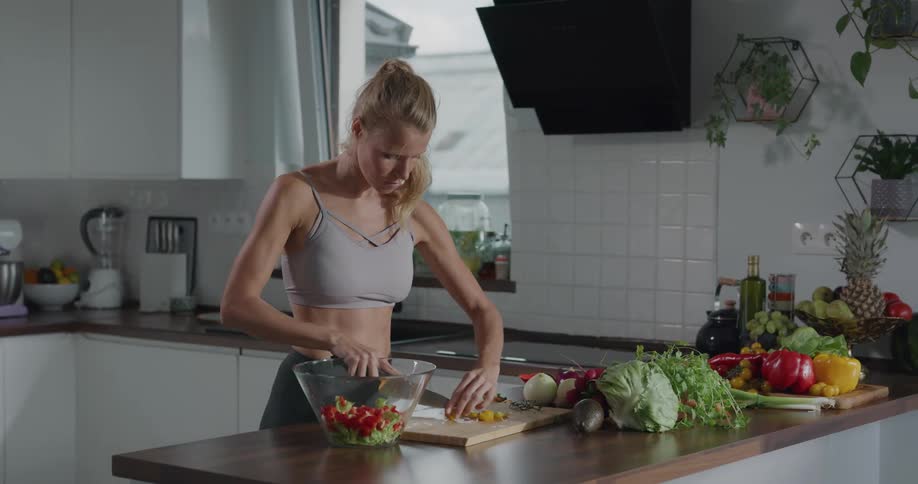 A woman cuts vegetables for a salad in her kitchen