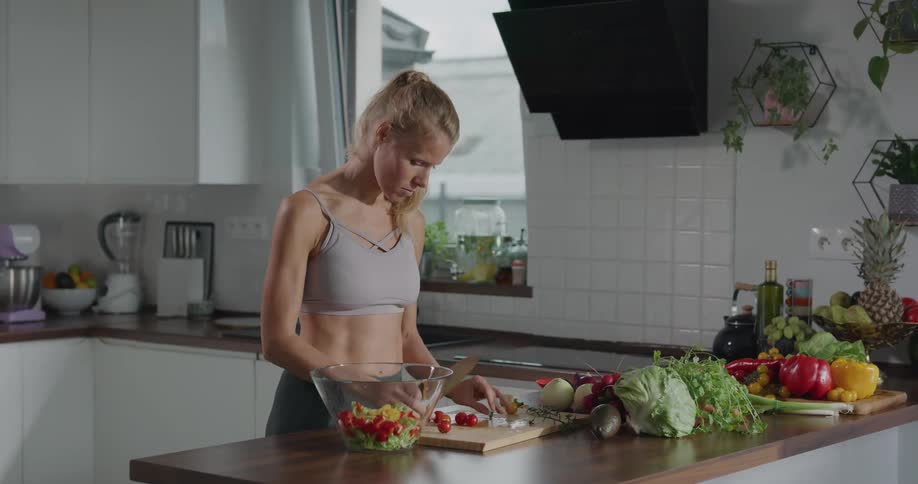 A woman cuts vegetables for a salad in her kitchen