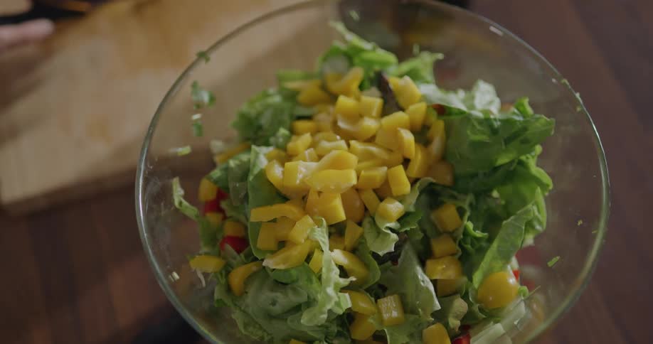 A woman puts vegetables in to a salad