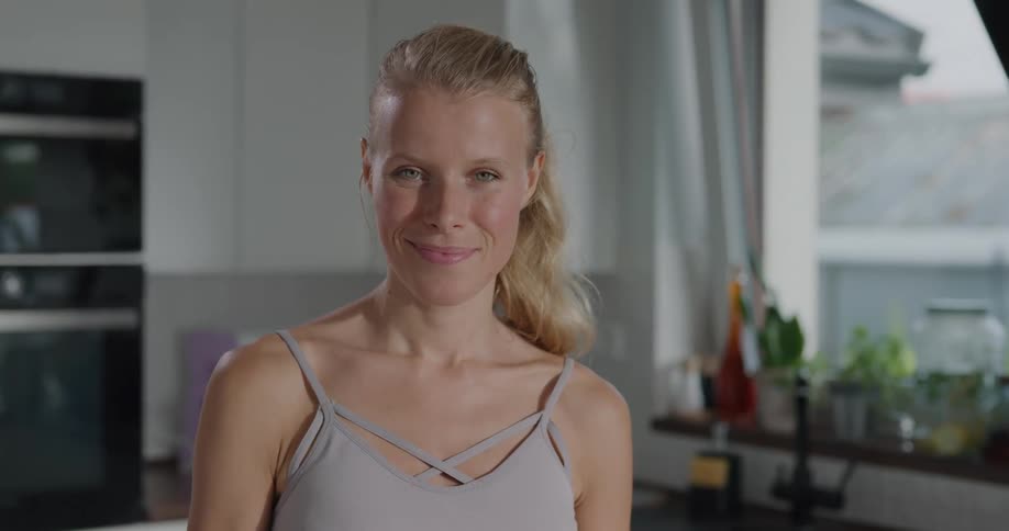 A woman cooking in her kitchen looks up and smiles