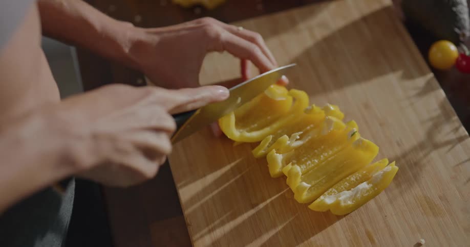 Woman sliced bell peppers on wooden chopping board on wooden counter