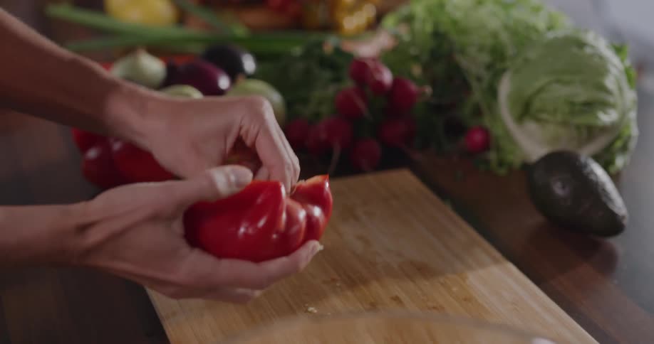 A young woman cuts a red pepper for a salad
