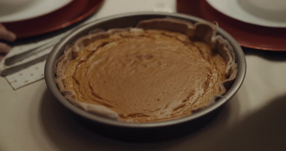 A pie with crust on a table next to plates and forks