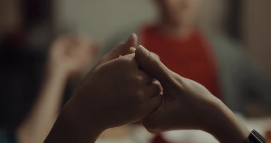 A family holds hands around the table as they pray