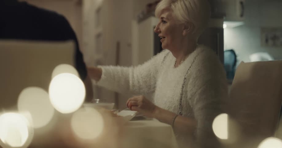 A woman raises a glass and toasts her family at the dinner table