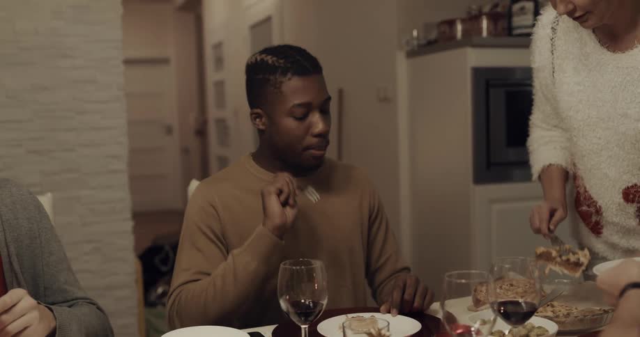 A man sits at a home dinner table and compliments the food being served