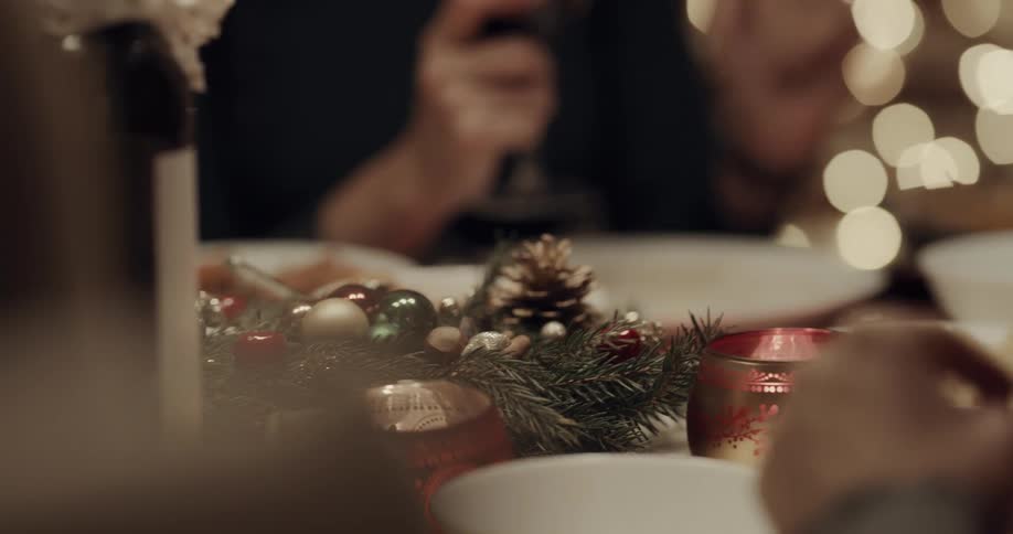 Centerpiece with pine branch and ornaments next to votive on table at christmas dinner