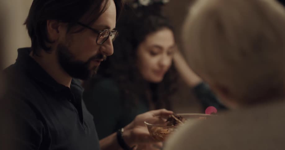 People in a dining room sitting at a table eating with a christmas tree in the background