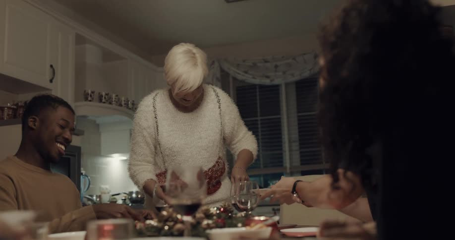 Woman serves dessert as people pass plates at christmas dinner party