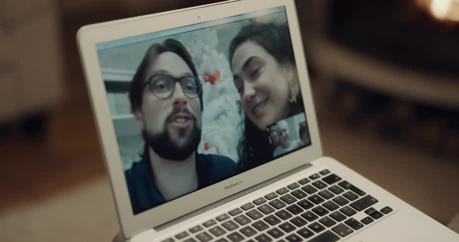 An elderly woman and her grandchildren use a laptop to video chat with a man and woman