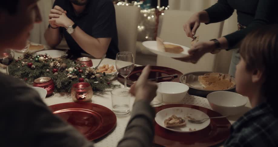 Standing woman serves pie to friends and family sharing christmas dinner