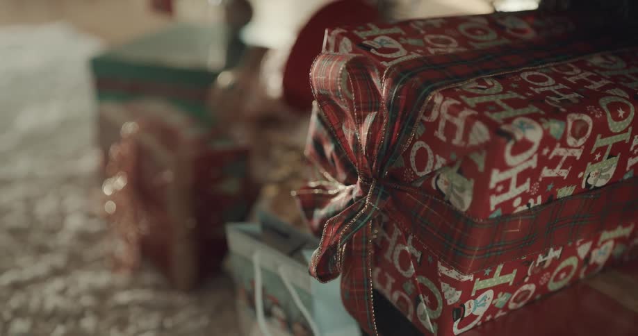 Festively wrapped christmas gifts sit on white rug on wooden floor