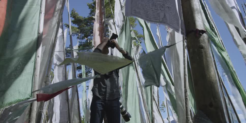 Man photographing waving flags on sticks on windy day