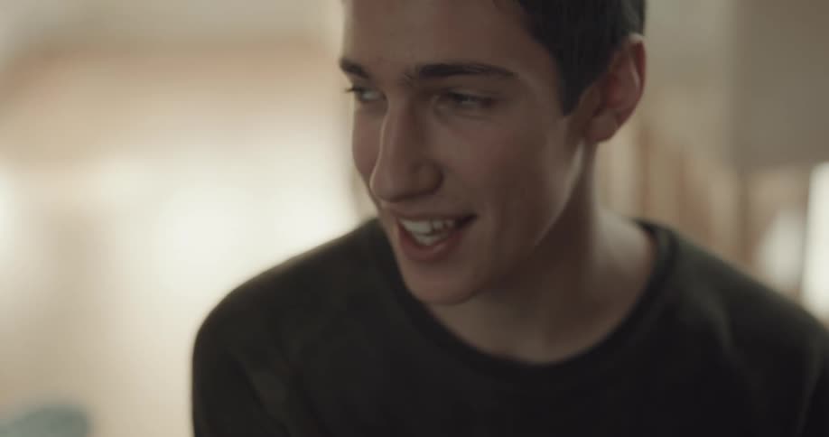 Man smiles and laughs while talking in room with back to window