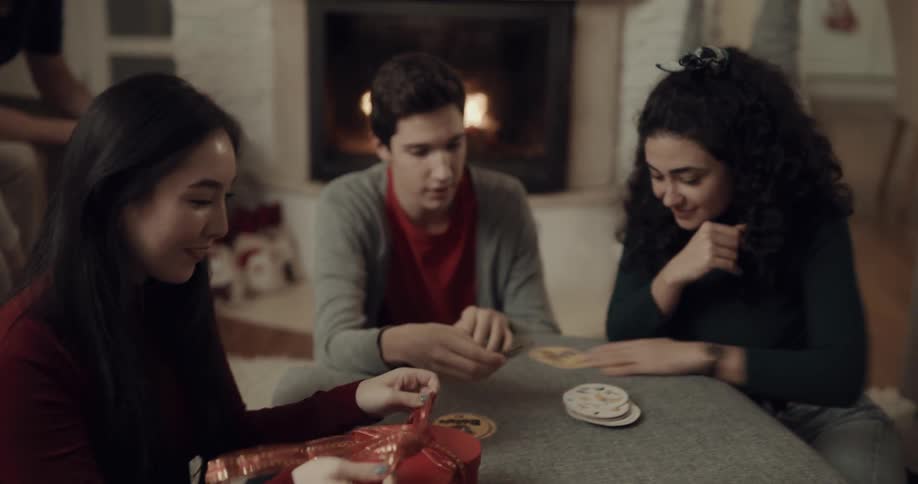 Two women and a man play a game while a young boy passes out gifts to people in the room