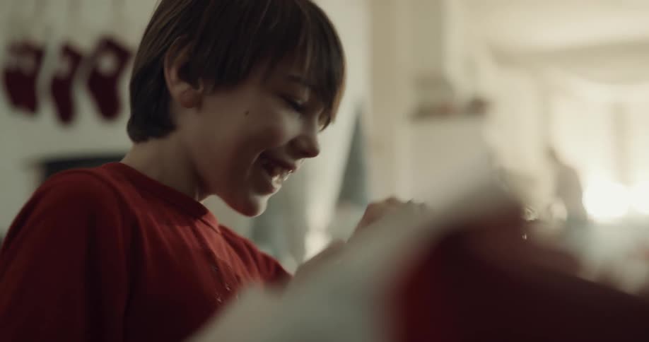 Boy rips wrapping paper off gift box happy and surprised at gift