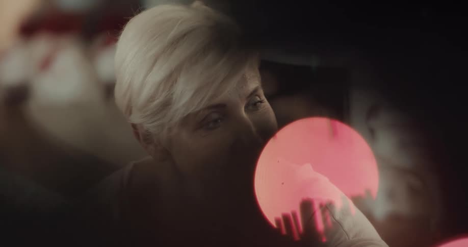 Adult short haired blonde woman listen and talks near the lights of a christmas tree
