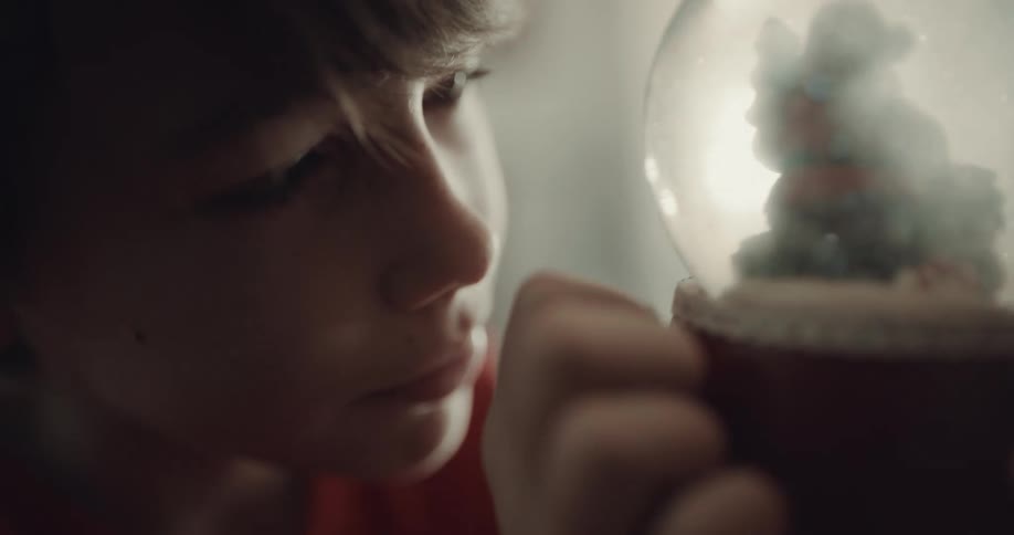 Boy examines snow globe with figure of santa claus