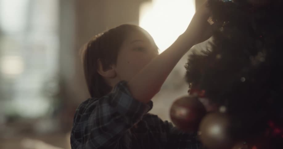 A young boy decorates a christmas tree at home