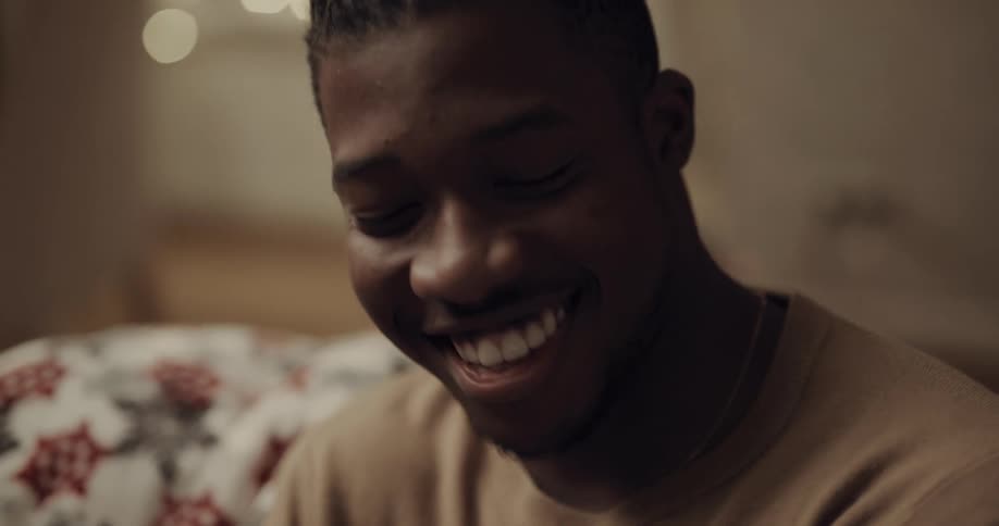 A young man sits inside a home talking and laughing