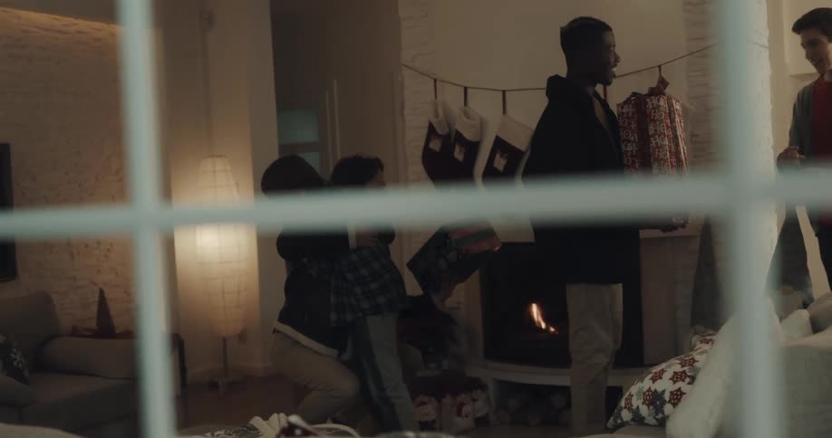 A young boy decorate a christmas tree and then three people carrying presents arrive and they all hug
