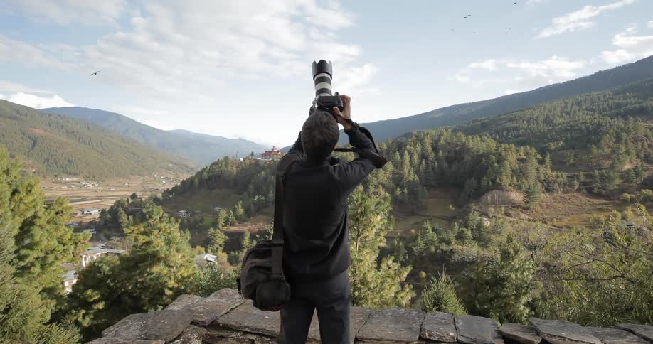 Man taking pictures of birds flying above him
