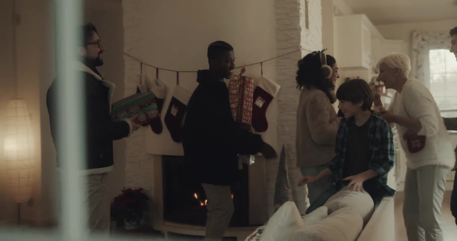 As a young boy decorates a christmas tree and his mother sets the table three people arrive carrying gifts and everyone hugs