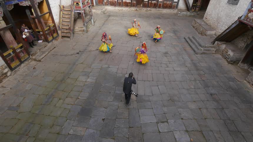 Dancers in traditional costume are photographed in an old courtyard