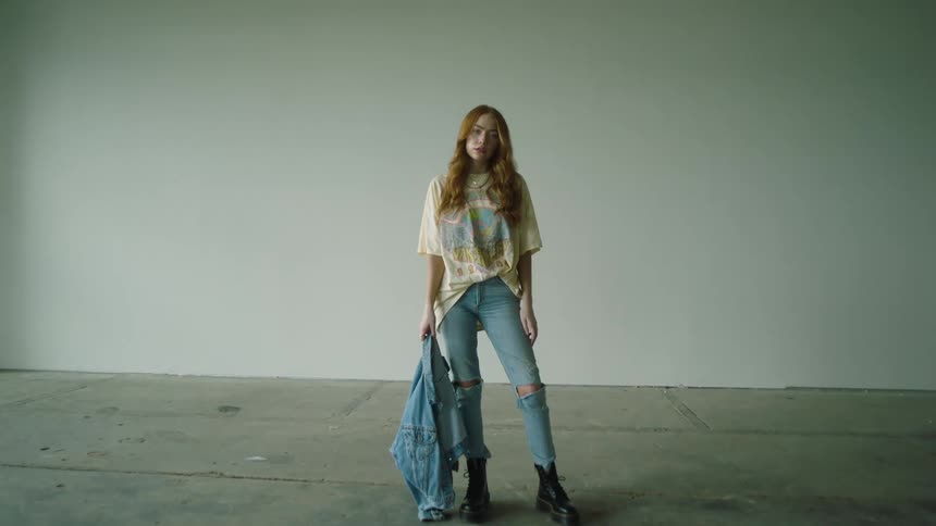 A girl stands on a concrete floor holding a jean jacket