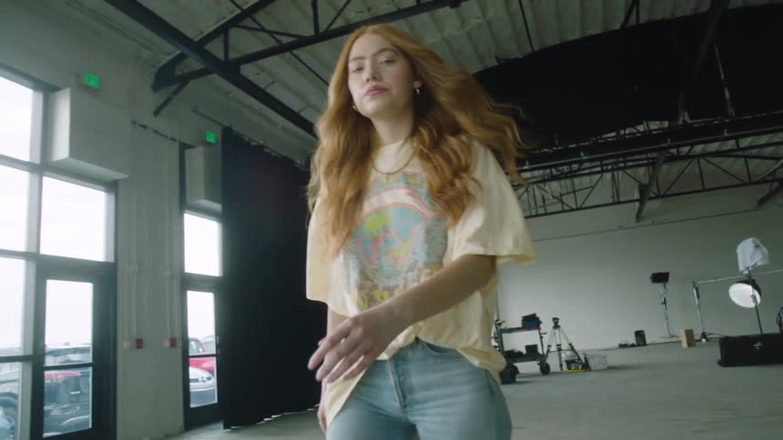 A young woman stares into the camera as she walks through a photography studio