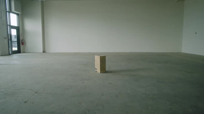 A wooden box in a large empty room with a cement floor
