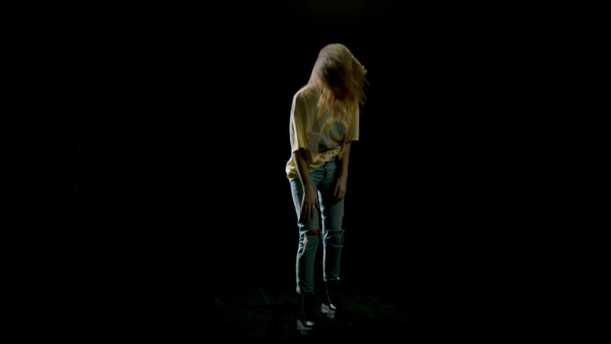 Woman swinging her hair back and forth in a dark room for a photo shoot
