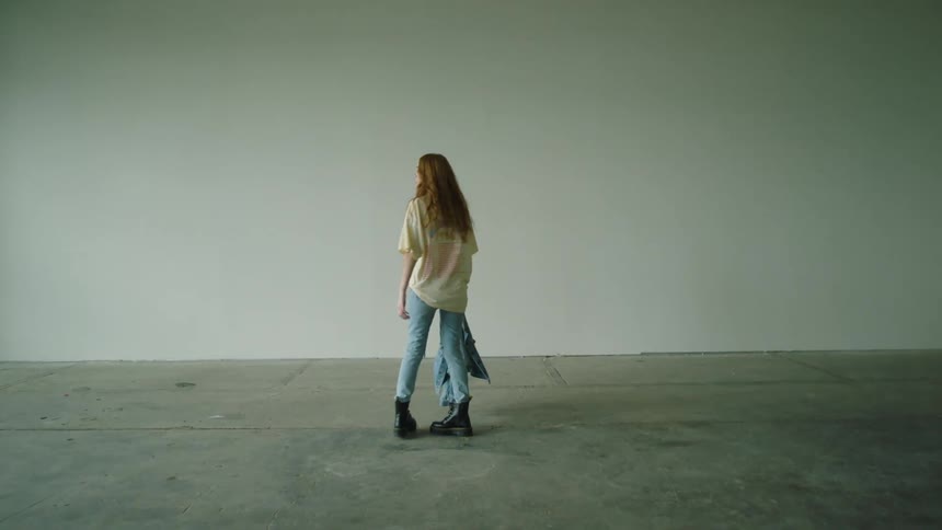 A woman standing and spinning in a room holding a jacket