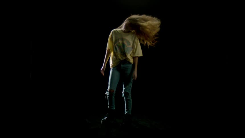 A young woman turning her body and flipping her hair towards a camera
