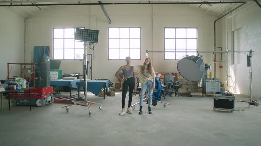 Two women stand side by side in a studio containing audio equipment