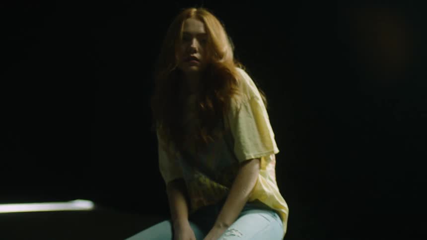Woman sits on a stool and moves to her left and right causing her long hair to swing back and forth