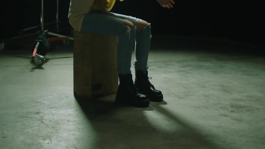 Young redhead woman sitting in a stool in the middle of a dimly lit studio