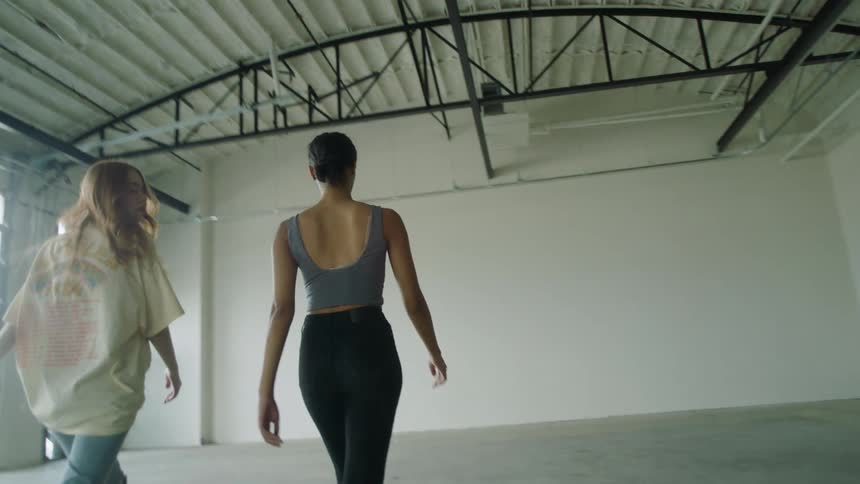 Couple of young fit girls walking inside a warehouse while looking at camera