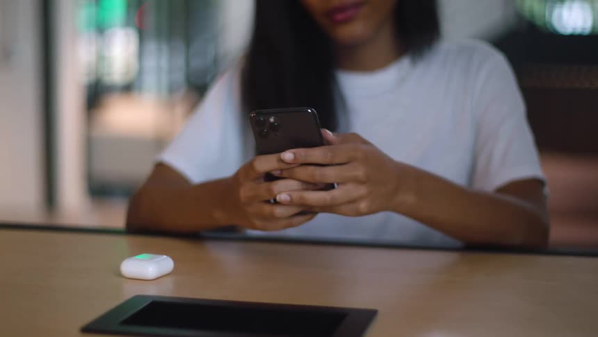 A black woman tapping on her smart phone at a desk in a building