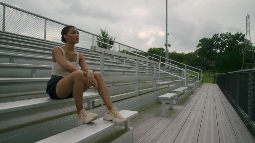 A black female sitting outside on bleachers