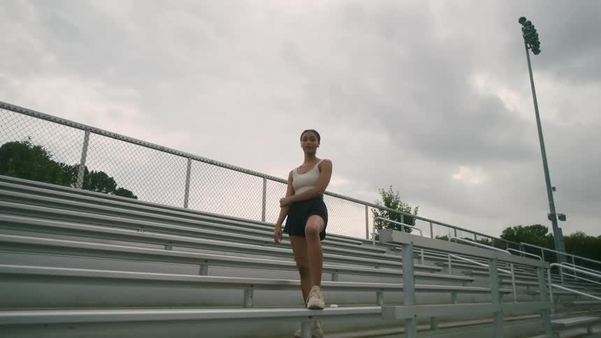 A woman is standing on bleachers outdoors