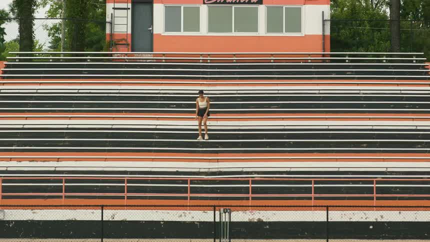 A girl walks on the bleachers in front of an announcers booth